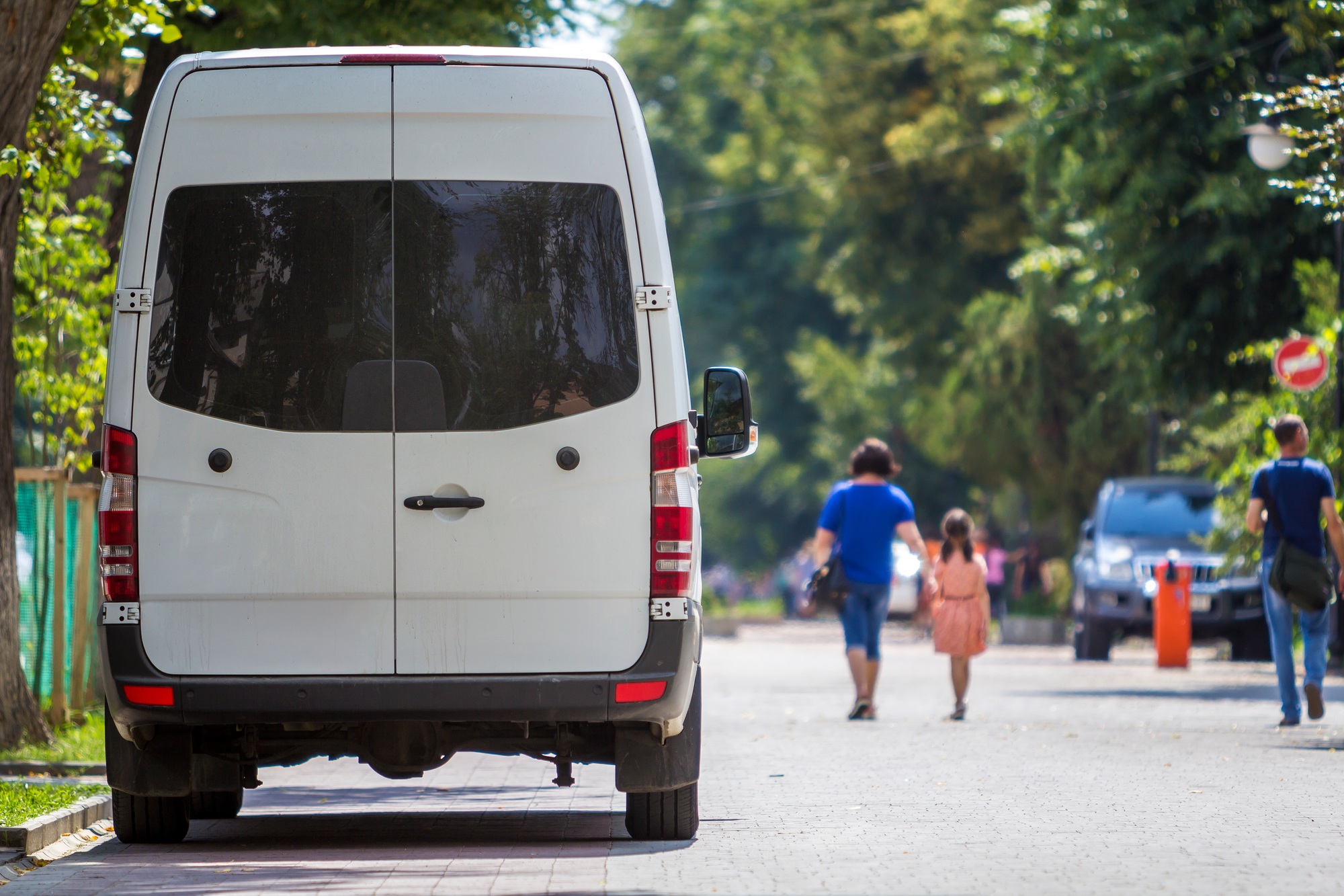 Back view white passenger medium size commercial luxury minibus van parked on summer city street
