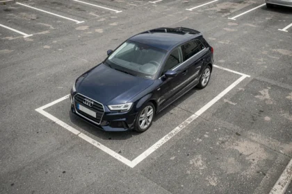 Audi A3 Sportback garée dans une place de parking urbaine délimitée par des lignes blanches, vue en plongée large