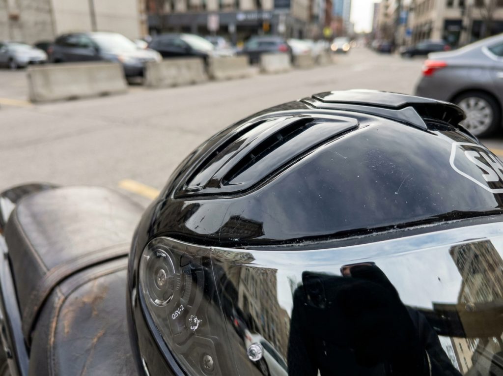 Gros plan sur les détails du casque Shoei GT Air 2 noir posé sur une selle moto, montrant les aérations, le mécanisme de visière solaire intégrée et la finition de la coque