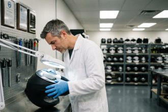 Ingénieur spécialisé inspectant l'intérieur d'un casque moto intégral noir mat dans un laboratoire de certification professionnel