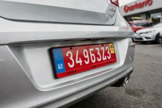 Plaque d'immatriculation provisoire rouge sur la pare-chocs arrière d'une voiture au parking d'une concession automobile